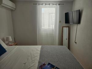 a bedroom with a bed with a television and a window at Apartman Sara-Vis in Vis