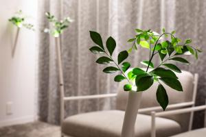 a white vase with a plant in front of a chair at SHIROIYA HOTEL in Maebashi
