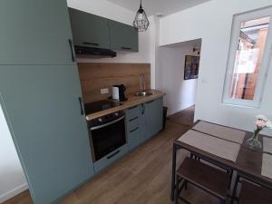 a kitchen with a stove and a table in it at L'olivier Maison de ville proche Cabourg in Dozulé +2 photos