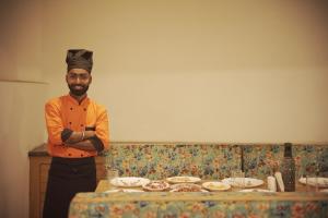 Un uomo con un cappello da chef in piedi davanti a un tavolo di Hotel Sherabling a Gangtok