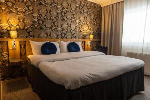 a bedroom with a large bed with blue pillows at Starby Spa, Hotell & Konferens in Vadstena