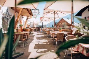 ein Restaurant mit Tischen, Stühlen und Sonnenschirmen in der Unterkunft Hotel Tradizio in Mittelberg