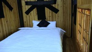 ein Bett in einem Zimmer mit einem Kreuz an der Wand in der Unterkunft MUONG HOA Peaceful HOMESTAY & Sapa in Lào Cai