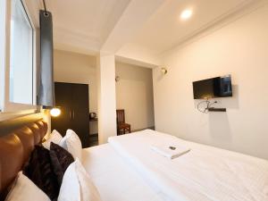 a bedroom with a white bed with a tv on the wall at Hotel Sherabling in Gangtok