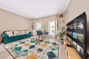 a living room with a blue couch and a tv at Battersea Bridge Ultra Central London One Bedroom Apartment 10 mins walk to Kings Road Chelsea in London
