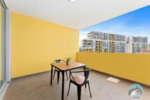 una mesa y sillas en un balcón con una pared amarilla en Aircabin - Mascot - Walk to Station - 2 Beds Apt en Sídney