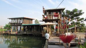 a house on a dock next to a body of water at Villa De Lumhun in Lamphun