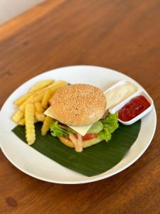 a plate with a hamburger and french fries and ketchup at Casa Lago Batur in Kubupenlokan
