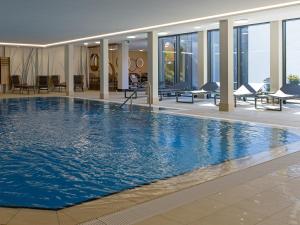 een groot zwembad met blauw water in een gebouw bij Hotel Schnitterhof in Bad Sassendorf