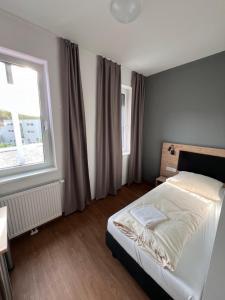 a bedroom with a white bed and a window at Firstsleep Ebersberg in Ebersberg