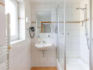 a white bathroom with a sink and a shower at Mercure Hotel Luebeck City Center in Lübeck