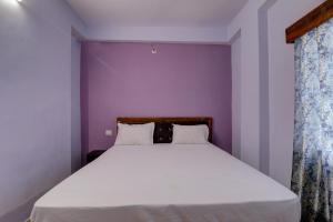 a bedroom with a white bed with a purple wall at Super OYO The Suncity Hotel in Patna