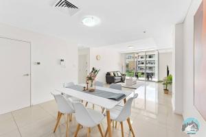 a white dining room with a white table and chairs at Aircabin - Mascot - Walk to Station - 3 Beds Apt in Sydney