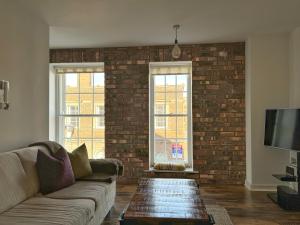 a living room with a couch and a brick wall at LUXURY spacious apartment next to Chester train station 10 min walk to Chester city center FREE parking The Old Post Office Apartment by Rework Accommodation in Chester