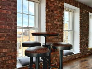 a room with three bar stools in front of a brick wall at LUXURY spacious apartment next to Chester train station 10 min walk to Chester city center FREE parking The Old Post Office Apartment by Rework Accommodation in Chester