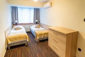 a hotel room with two beds and a dresser at Ośrodek Szkoleniowo-Wypoczynkowy "Leśnik" in Ustka