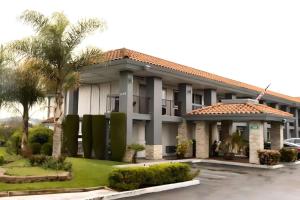 圣何塞Rodeway Inn San Jose HWY-101 Tully Rd Exit的停车场里有一栋种有棕榈树的建筑