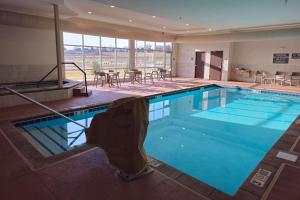 a large swimming pool in a hotel with tables and chairs at Comfort Inn & Suites at Sanford Sports Complex in Sioux Falls