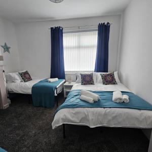 a bedroom with two beds and a window with blue curtains at Lyndhurst Terrace, Sunderland in Trimdon Grange