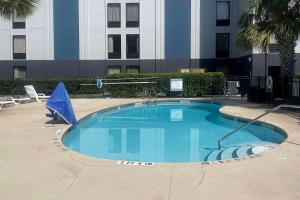 a large swimming pool with a blue umbrella in front of a building at Quality Inn Southside Jacksonville in Orange Park