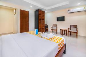 a bedroom with a large bed and chairs at FabHotel Krishna Residency in Chennai