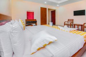 a bedroom with a large white bed with chairs at FabHotel Krishna Residency in Chennai