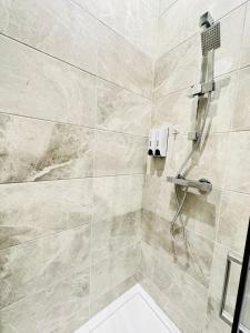 uma casa de banho com um chuveiro com azulejos bege em Studio 64 em Londres