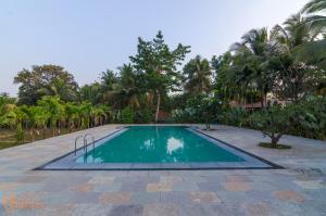 a swimming pool in a resort with palm trees at Jomo Resort in Alībāg