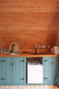 cocina con armarios azules, fregadero y paredes de madera en Sea View Pod Close to Mountains / Snowdonia en Caernarfon