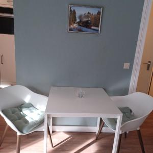 une table à manger blanche et deux chaises blanches dans l'établissement Wandertraum, à Braunlage