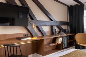 a room with a bed and a desk with a tv at Hotel Le Colombier in Obernai