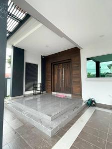 una veranda anteriore di una casa con porta in legno di 1717 Bintulu Homestay 11 a Bintulu