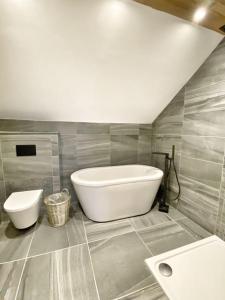 baño con bañera blanca grande y aseo en MEILA COTTAGE LUXURY COASTAL RETREAT, en Cubert