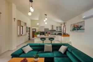 uma sala de estar com um sofá verde e uma cozinha em Villa Alora em Pridraga