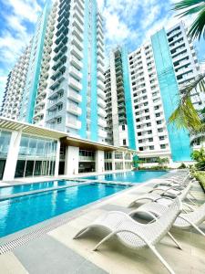 a swimming pool with chairs in front of tall buildings at Ezren Suites Mesavirre Residences Unit922 in Bacolod