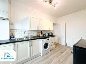 a kitchen with white cabinets and a washer and dryer at Free Parking - Family Stays - Spacious in Harrogate