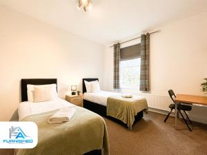 um quarto com 2 camas, uma secretária e uma janela em Free Parking - Family Stays - Spacious em Harrogate