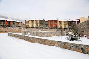 Domotel Neve Mountain Resort في بالايوس أجيوس أثناسيوس: مدينة مغطاة بالثلج مع مباني في الخلفية