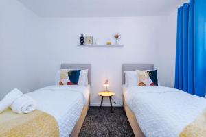 - 2 lits jumeaux dans une chambre avec des rideaux bleus dans l'établissement 3 Bed+2 Bath Perfect Contractors & Groups, à Ocker Hill