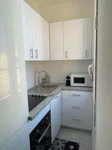 uma cozinha com armários brancos, um lavatório e um micro-ondas em Monaco Cosy 3 pièces em Saint-Antoine