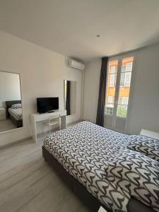 a white bedroom with a bed and a television at Monaco Cosy 3 pièces in Saint-Antoine