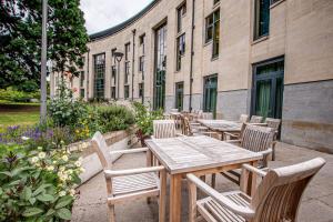 a patio with wooden tables and chairs in front of a building at Stephen Hawking Building Gonville and Caius College in Cambridge