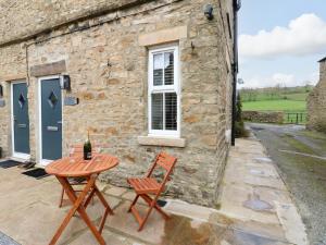 - une table et des chaises à l'extérieur d'un cottage en pierre dans l'établissement Larl Cottage, à Barnard Castle