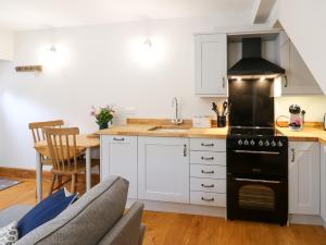kuchnia z białymi szafkami i czarną kuchenką w obiekcie Larl Cottage w mieście Barnard Castle