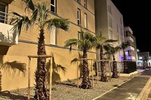 a group of palm trees in front of a building at T2 Appartement Sunset Lodge à 250 m de la mer, 3 couchages in Narbonne-Plage