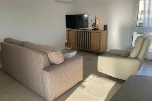 a living room with a couch and a chair and a tv at T2 Appartement Sunset Lodge à 250 m de la mer, 3 couchages in Narbonne-Plage