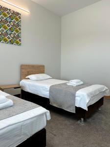 Habitación con 3 camas y sábanas blancas. en PORT INN Hotel en Astaná