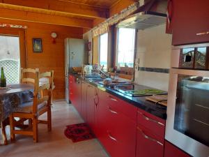 uma cozinha com armários vermelhos, um lavatório e uma mesa em Le chalet sur la dune em Plouguerneau