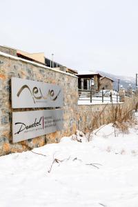 a sign on a building in the snow at Domotel Neve Mountain Resort in Palaios Agios Athanasios