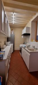 a large kitchen with white cabinets and appliances at Maison cœur de ville aux Portes du Morvan in Corbigny